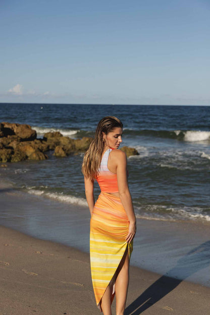 Model in one-shoulder cover up dress at beach back view