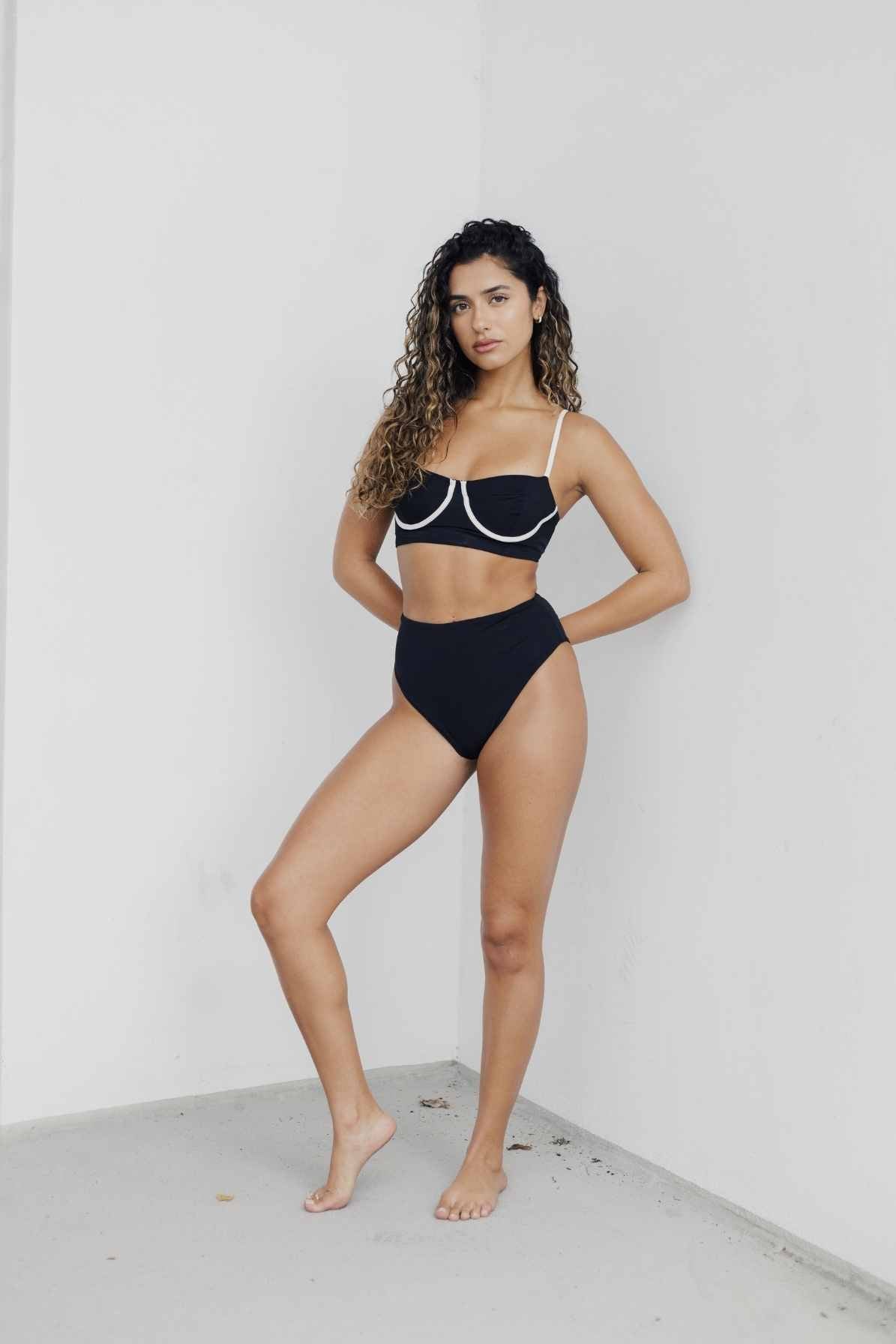 Model standing wearing black swimsuit